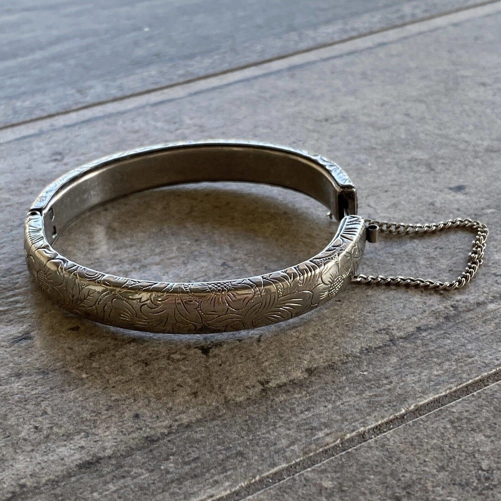 A beautiful vintage cuff bracelet with floral design features safety chain